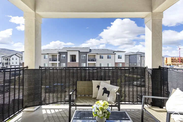 Covered outdoor balcony with sturdy support columns, black metal railings, and a privacy screen