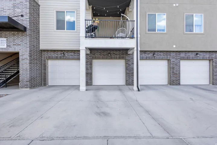 Exterior featuring a combination of brick and siding, multiple garage doors, and a private balcony