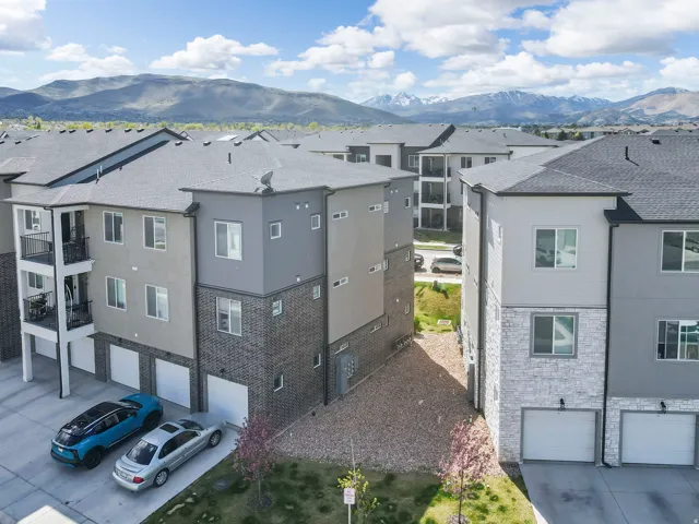 Contemporary multi-level townhome featuring a mix of siding and brick facades, individual garages, and private balconies with black railings