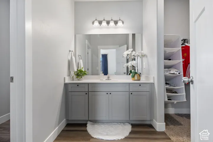 Bathroom vanity featuring a light gray cabinet base with six doors, a white countertop, and an undermount sink