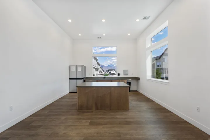 Open concept space featuring wood-finish flooring, a central island with a solid surface countertop, and stainless steel appliances