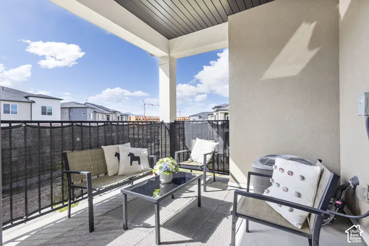 Covered outdoor balcony featuring a textured ceiling, stucco wall finishes, and a black wrought iron railing