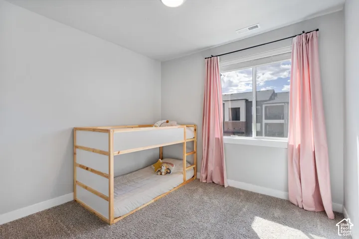Bright room featuring a large window, neutral wall paint, and soft carpet flooring