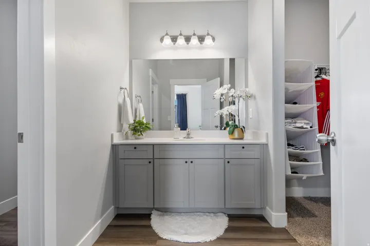 Bathroom vanity featuring a light gray cabinet base with six doors, a white countertop, and an undermount sink