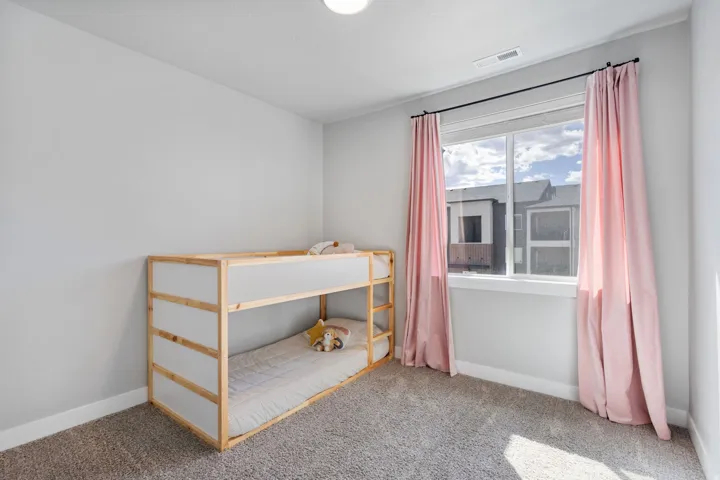 Bright room featuring a large window, neutral wall paint, and soft carpet flooring