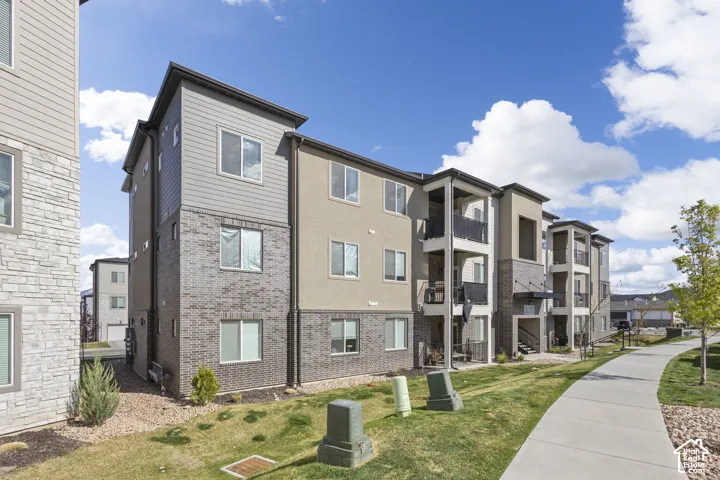 Multi-story residential building featuring a combination of horizontal siding, brick facade, and stucco finishes