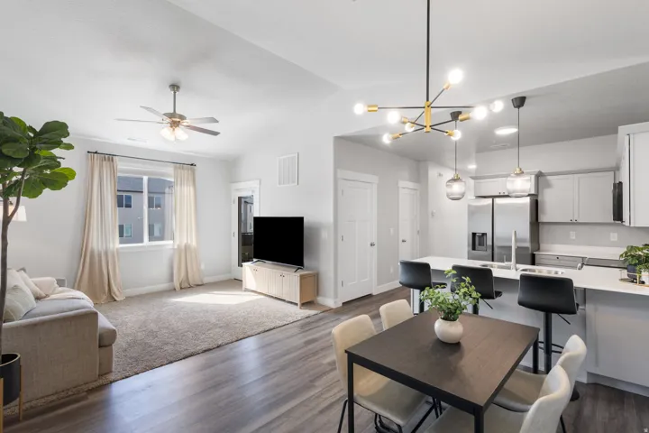 Open-concept living space featuring vaulted ceilings, wood-finish flooring, and a modern chandelier