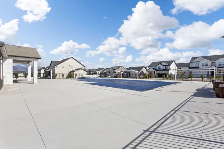 Community swimming pool with a covered pool house and ample concrete decking, surrounded by contemporary residences