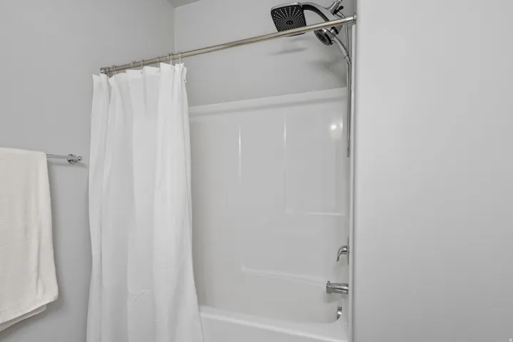 Tub and shower combination featuring a white surround, chrome fixtures, and a multi-function shower head