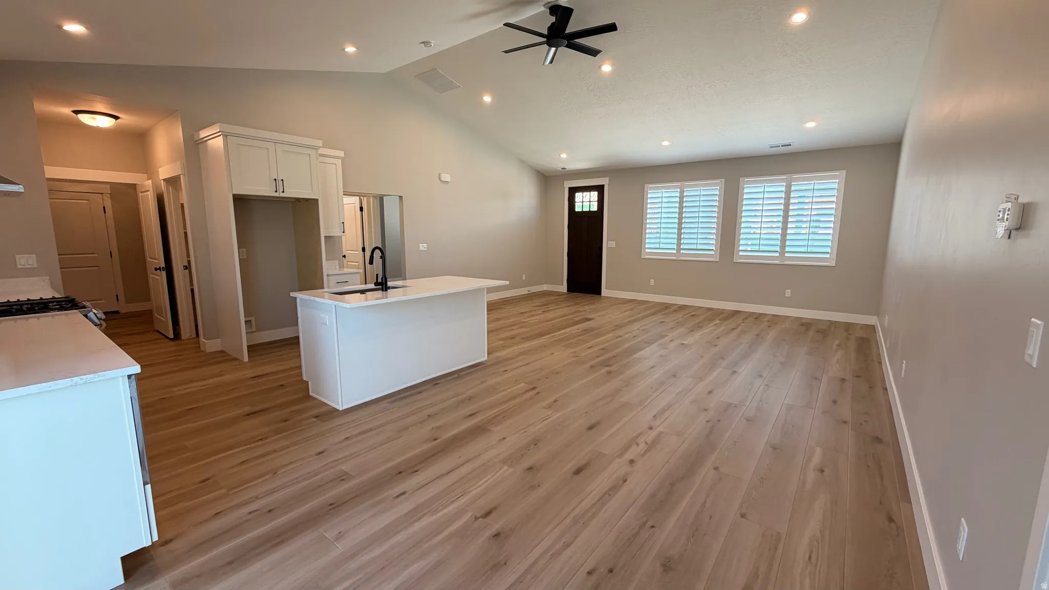 Open concept living space featuring wood-finish flooring and a vaulted ceiling