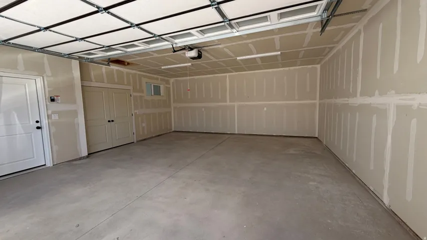 Spacious garage featuring a concrete floor, overhead garage door with opener, and ample wall space
