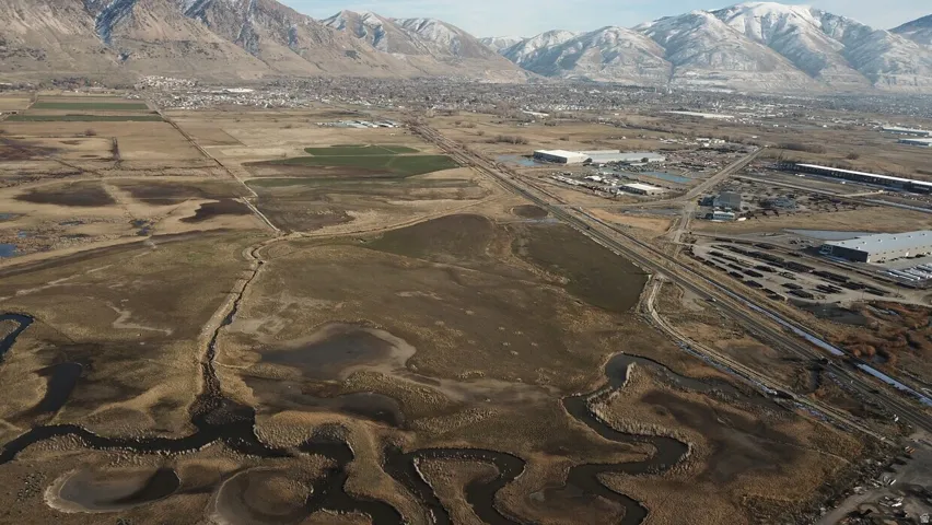 Expansive aerial perspective showcasing diverse terrain with a meandering waterway, agricultural fields, and developed areas