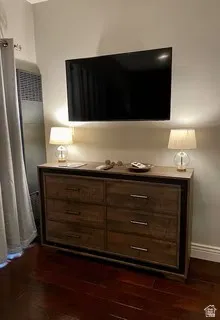 Wall-mounted television above a six-drawer dresser with metal hardware and a wood-finish surface