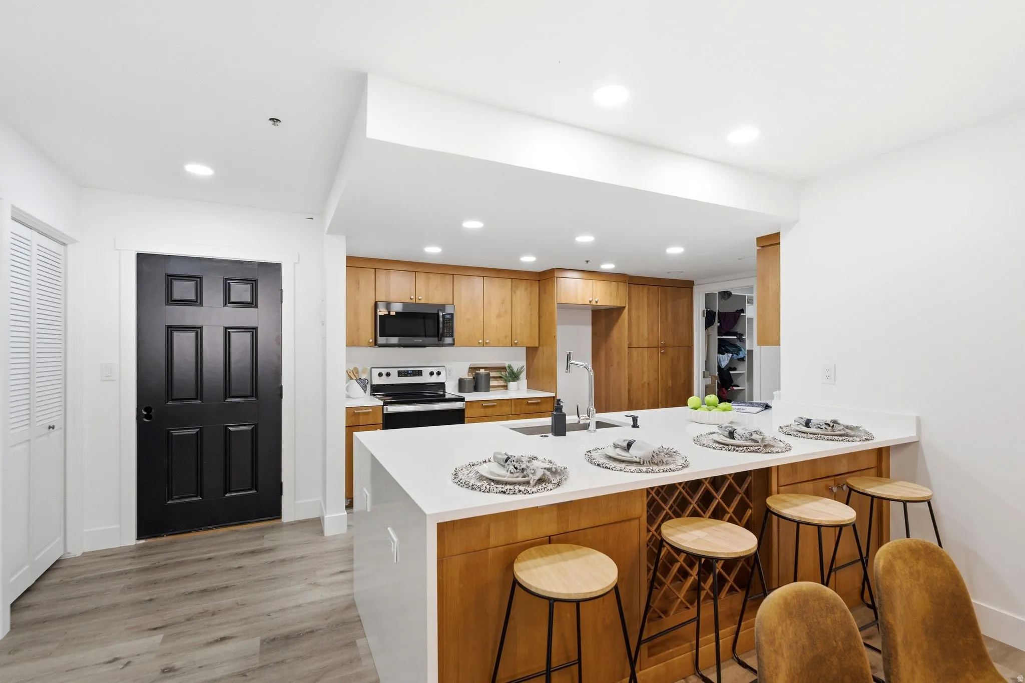 Modern kitchen featuring wood-finish cabinetry, stainless steel appliances, and light-tone countertops