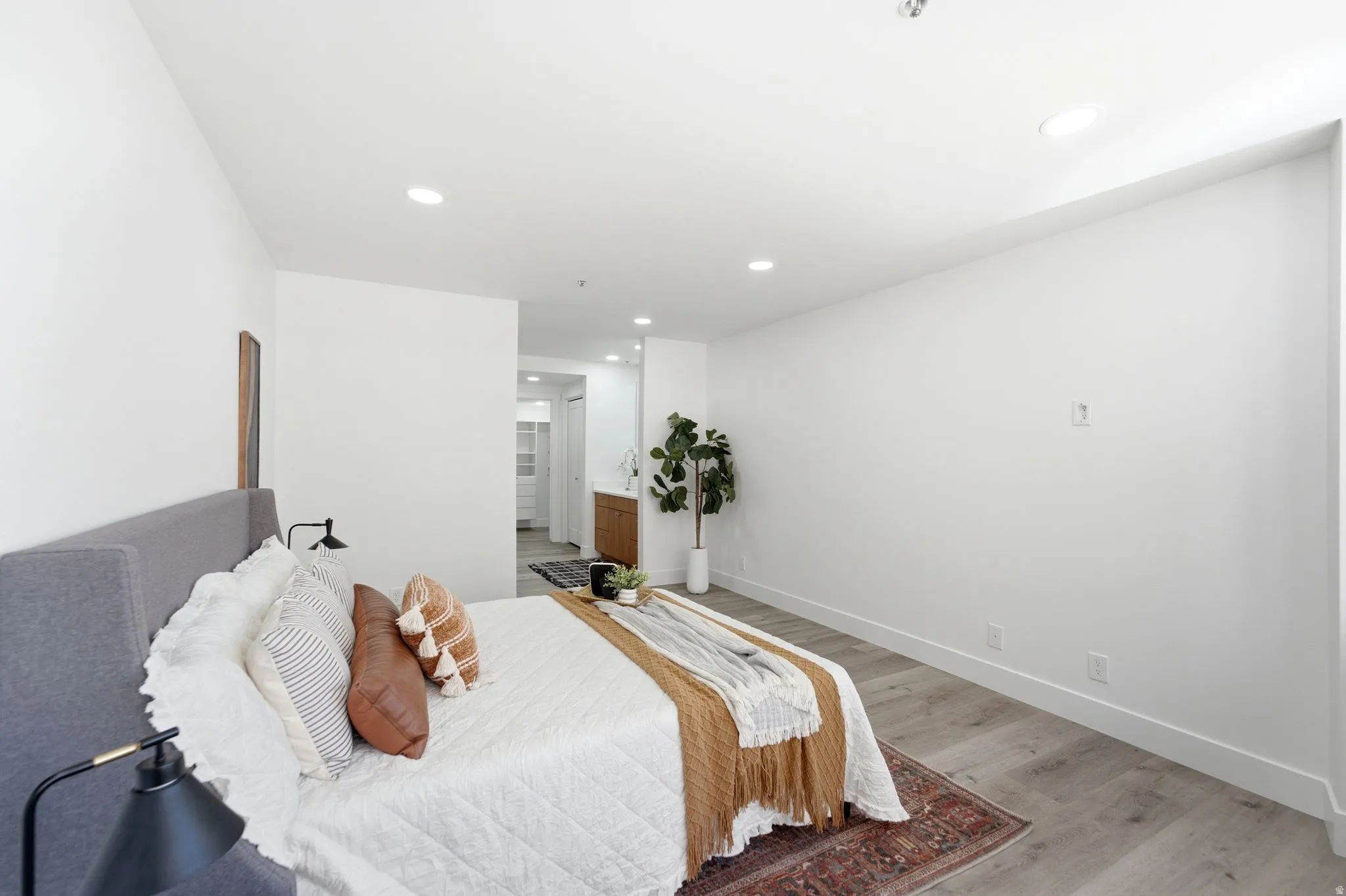 Spacious master bedroom interior featuring recessed lighting, wood-finish flooring, and white baseboards