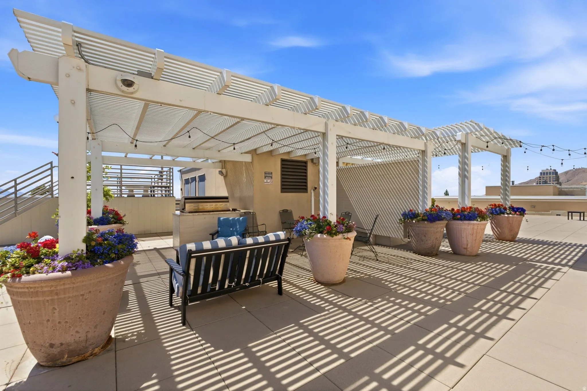 Rooftop patio with an expansive white pergola and string lighting