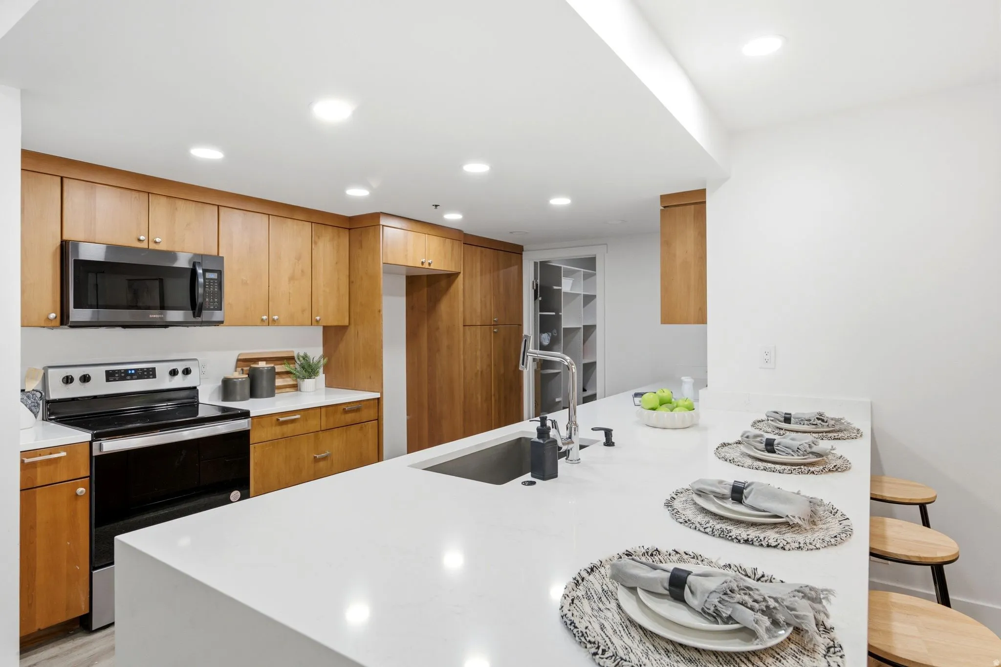 Kitchen featuring a large central island with integrated sink, stainless steel appliances, abundant cabinetry, and recessed lighting