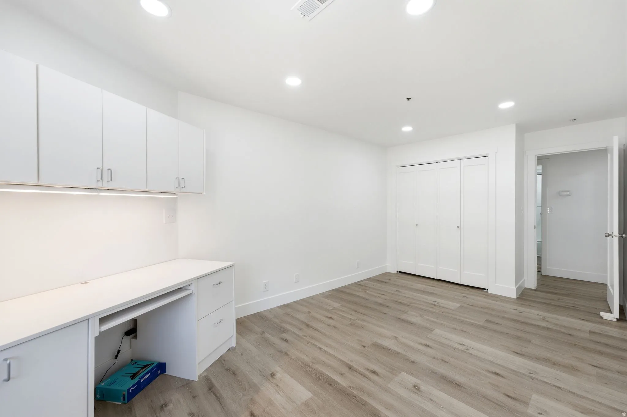 Spacious second bedroom with Dedicated workspace featuring built-in white cabinetry, under-cabinet lighting, and a desk area