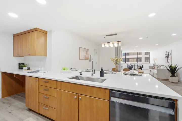 Modern kitchen featuring light wood cabinetry, white countertops, and a stainless steel sink with a matte black faucet
