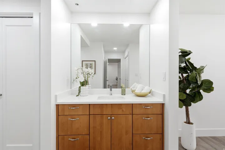 Master Bathroom vanity featuring a light wood-finish cabinet with varied drawer and door configurations, a white countertop, and an integrated rectangular sink