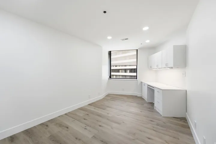 Second bedroom feat. Built-in desk with overhead cabinetry, recessed lighting, and wood-finish flooring