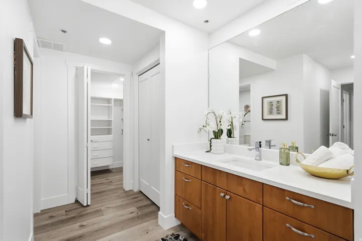 Master Bathroom vanity with a white countertop and integrated sink, wood-finish cabinetry, and a large wall-mounted mirror