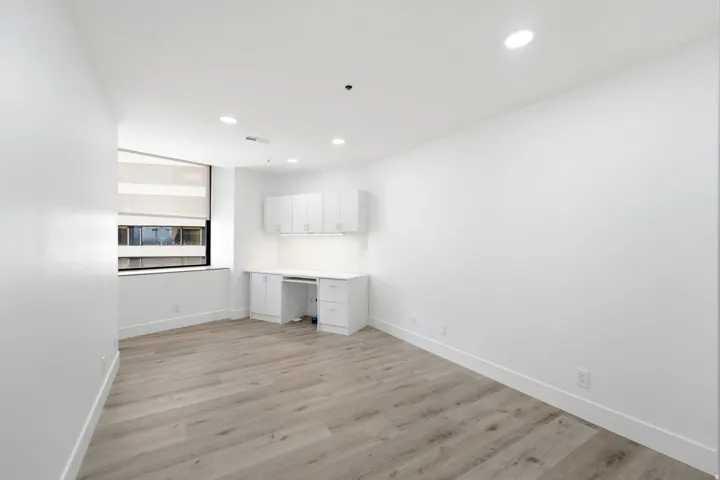 Second bedoom featuring wood-finish flooring, recessed lighting, and a built-in desk with white cabinetry