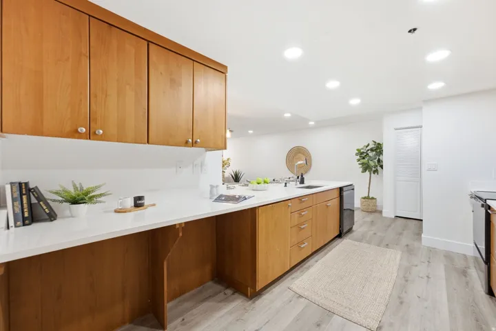 Kitchen featuring wood cabinetry, white countertops, built-in dishwasher, recessed lighting, and wood-finish flooring