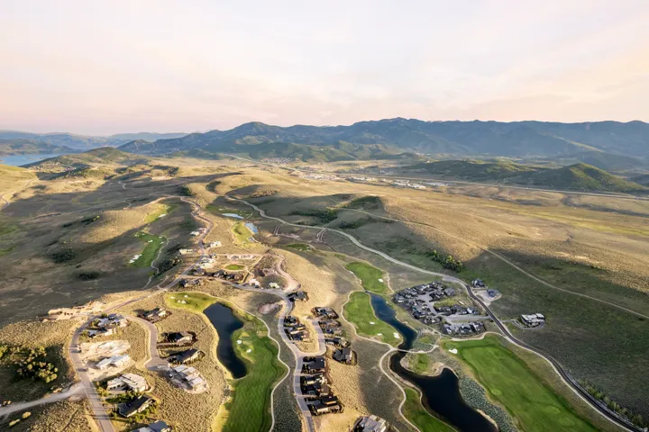 Expansive aerial view showcasing a golf course community with multiple homes, manicured greens, and water features