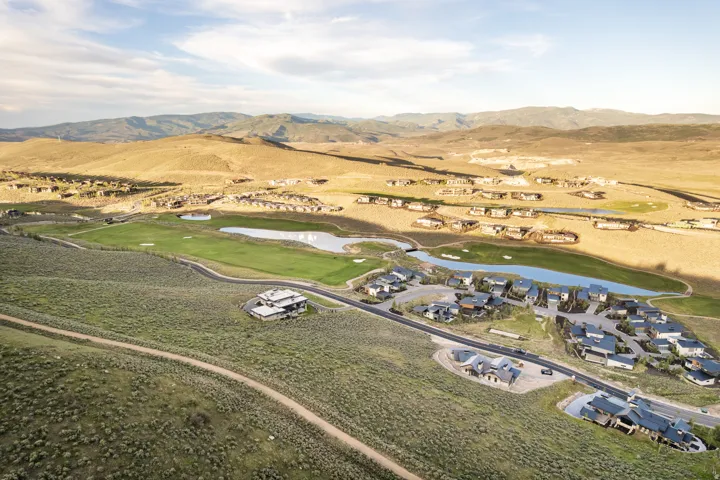 Expansive natural landscape featuring multiple residential properties, a golf course with green fairways, and water features
