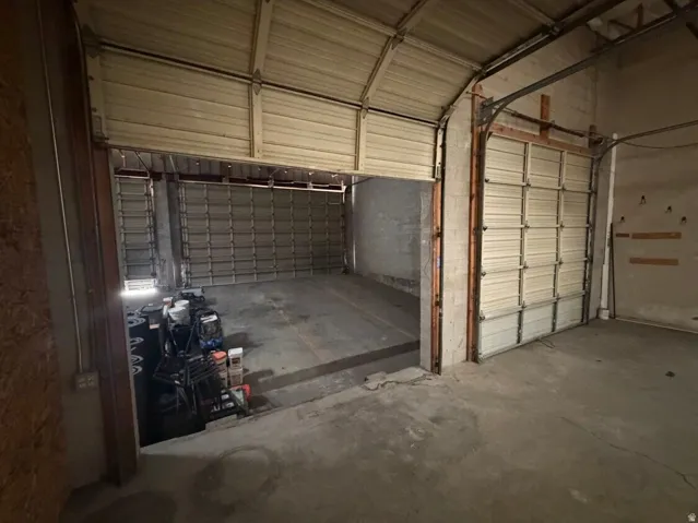 Industrial space featuring concrete flooring, multiple overhead doors, and high ceilings