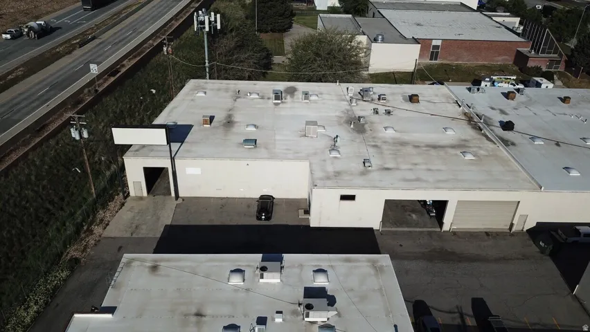 Commercial building featuring multiple roof-mounted skylights, a large exterior sign frame, and a garage door entrance