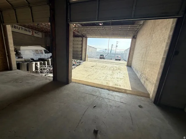 Industrial interior featuring a concrete floor, two open bay doors, and exposed ceiling trusses