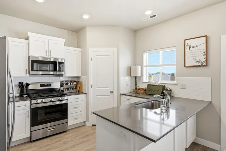 Contemporary kitchen featuring white cabinetry, stainless steel appliances, a subway tile backsplash, and wood-finish flooring