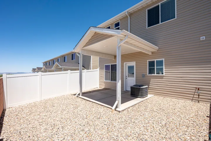 Private outdoor patio featuring a concrete slab and a durable vinyl fence