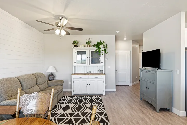 Living area featuring plank accent wall, ceiling fan, and wood-finish flooring