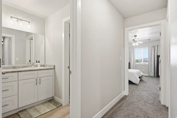 Bathroom vanity with white cabinetry and a light-toned countertop, featuring a rectangular sink and brushed nickel hardware
