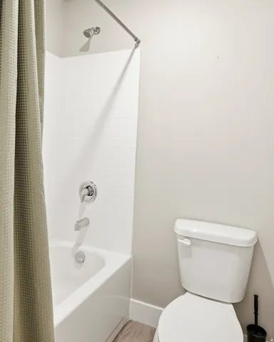 Bathroom featuring a white porcelain toilet, a white bathtub, and white subway tile surround