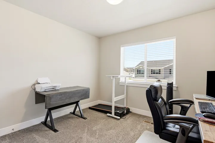 Bright room featuring a large window with blinds, neutral wall paint, and gray carpet flooring
