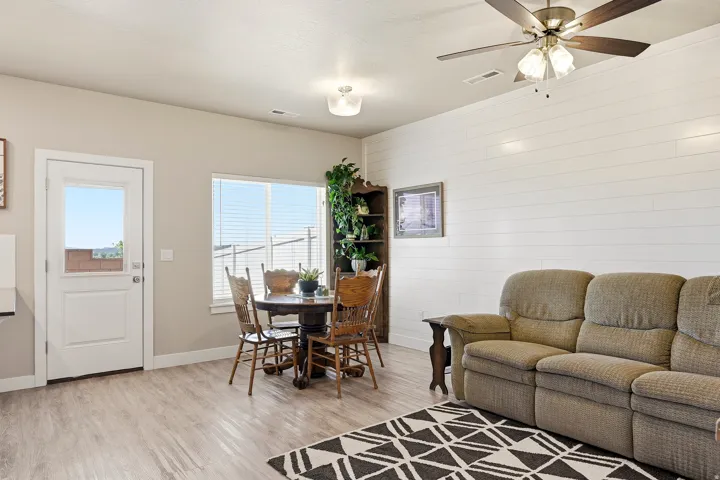 Open-concept living area featuring wood-finish flooring, a contemporary ceiling fan, and a prominent shiplap accent wall