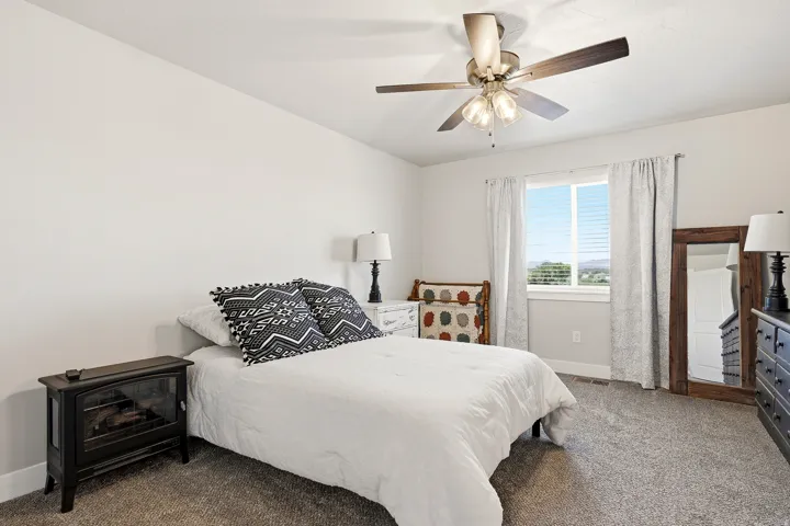 Carpeted room featuring a ceiling fan with integrated lighting, a window with horizontal blinds, and white baseboards