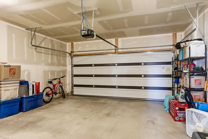 Garage featuring a sectional overhead door with an automatic opener, concrete flooring, and exposed ceiling joists
