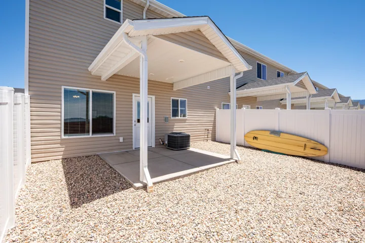 Private rear yard featuring a covered concrete patio, light-toned siding, and a white vinyl fence