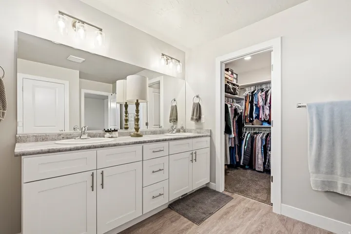 Double vanity featuring white cabinetry, integrated sinks, a continuous countertop, and overhead lighting