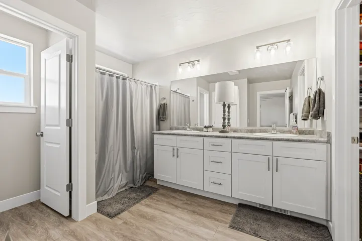 Bathroom featuring a double vanity with white cabinetry, light-toned countertop, and dual sinks