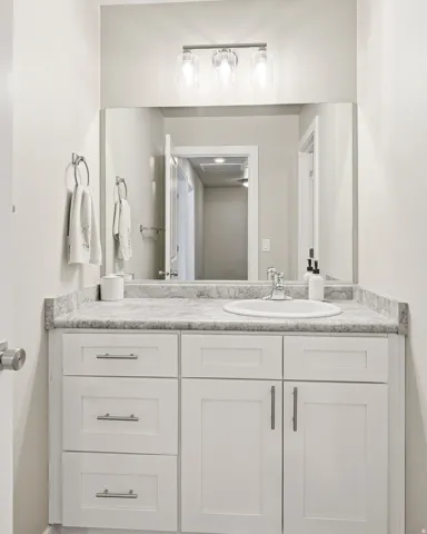 Bathroom vanity with a white rectangular sink, a stone-finish countertop, and a chrome faucet