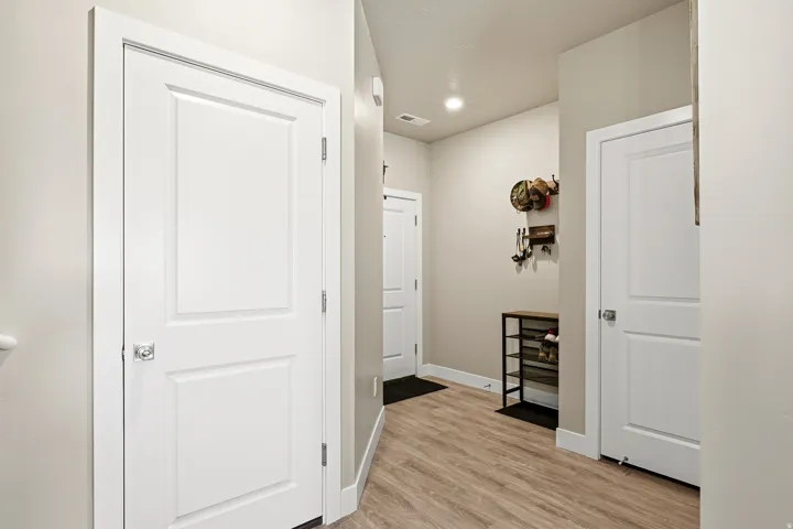 Entryway featuring wood-finish flooring, recessed lighting, and white paneled doors with contemporary hardware