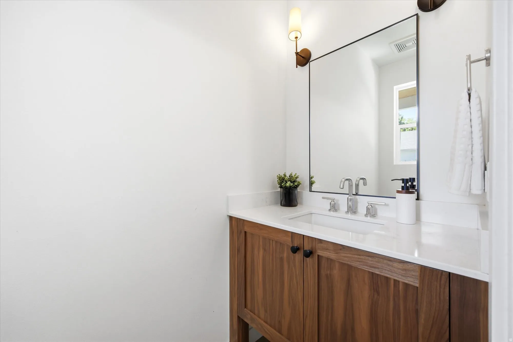 Wood-finish vanity with a white countertop and undermount sink