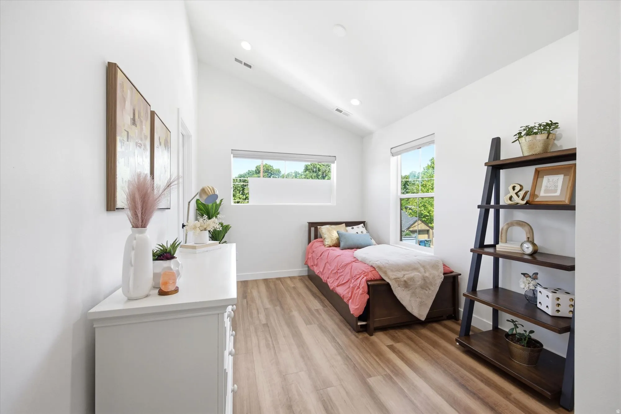 Spacious room featuring vaulted ceilings, recessed lighting, wood-finish flooring, and large windows providing natural light