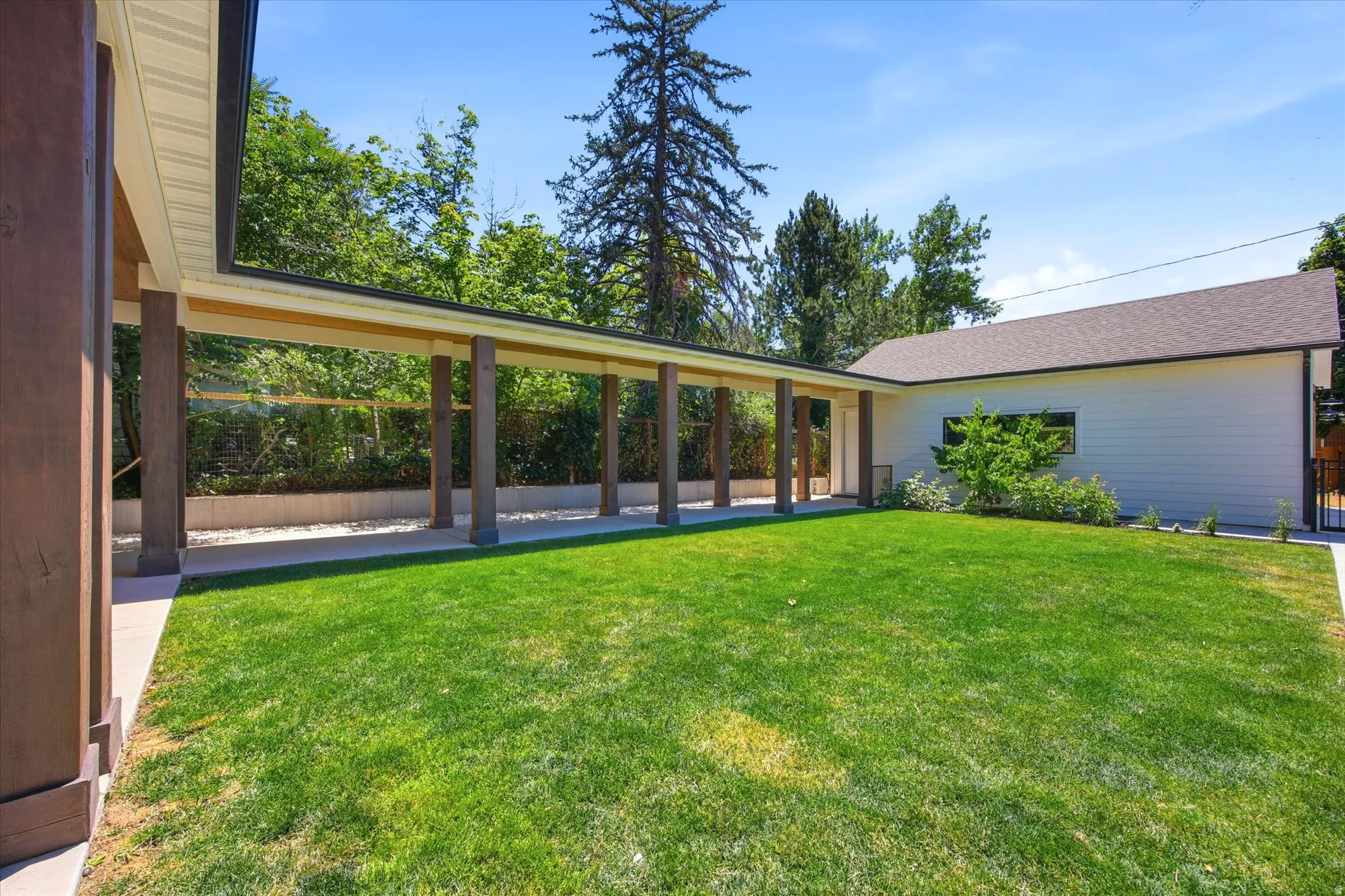 Expansive green lawn area with a covered walkway featuring multiple columns